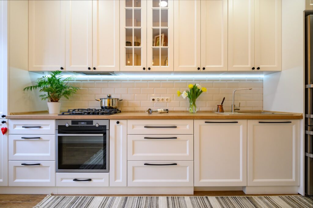 Bright kitchen with white cabinets, built-in oven, gas cooktop, and under-cabinet lighting