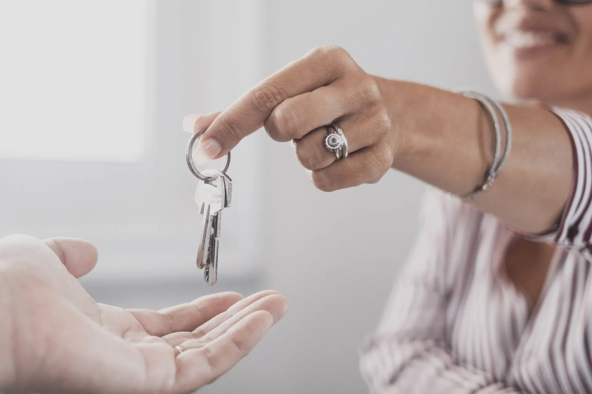 Person handing over a set of keys, symbolizing moving into an apartment