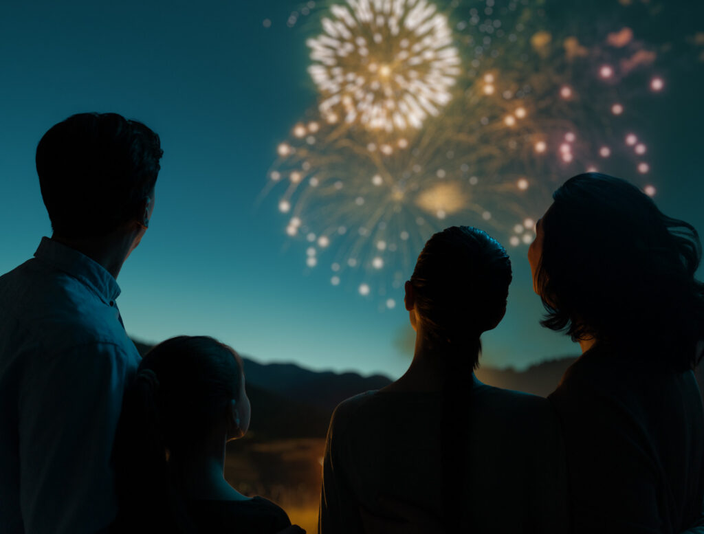 People sitting together at dusk, looking up at a sunlit sparkling aurora-like light display