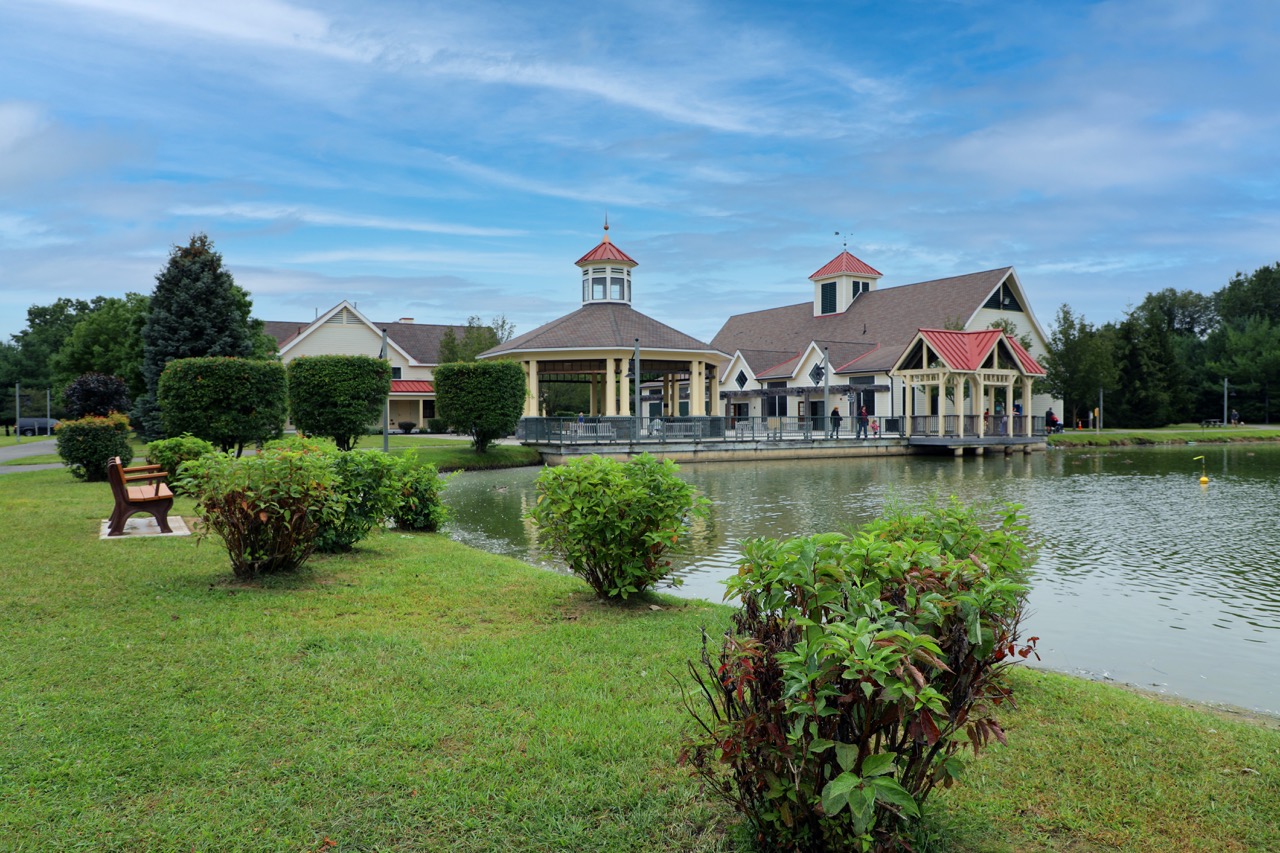 Lakeside apartment clubhouse exterior with covered porch and gazebo under a blue sky